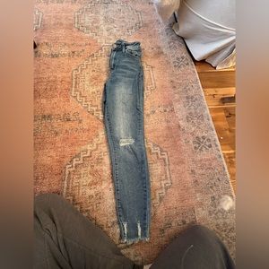 YMI blue jeans with one hole in the left knee and distressed bottom.